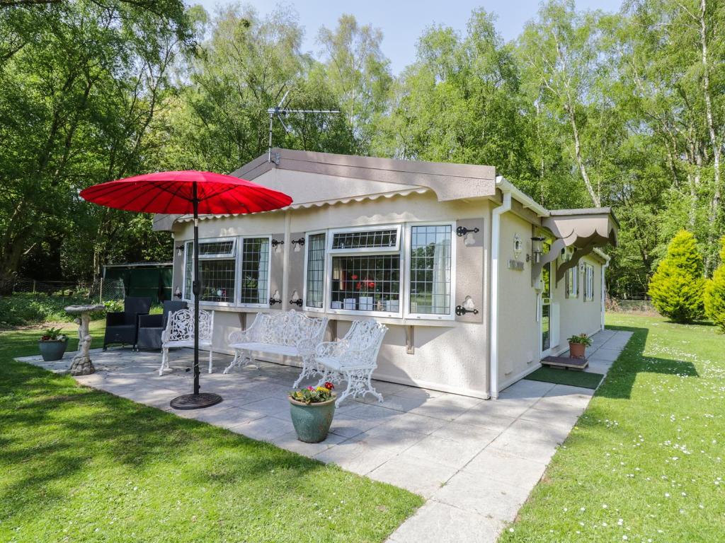 a small white shed with a red umbrella at The Lodge in Attleborough