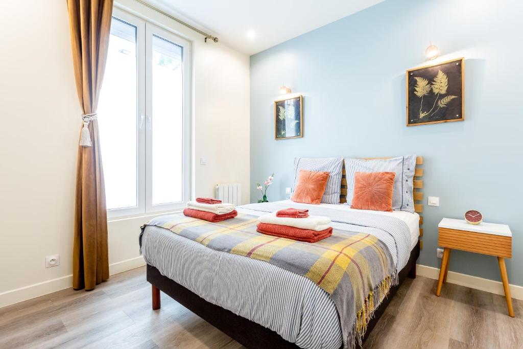 - une chambre dotée d'un lit avec des oreillers orange dans l'établissement StayLib - GARIBALDI 2 PIECES PORTE DE MONTMARTRE, à Saint-Ouen