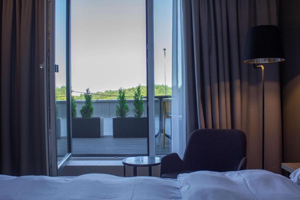 a hotel room with a bed and a chair and a balcony at Park Inn by Radisson Vilnius Airport Hotel & Conference Centre in Vilnius