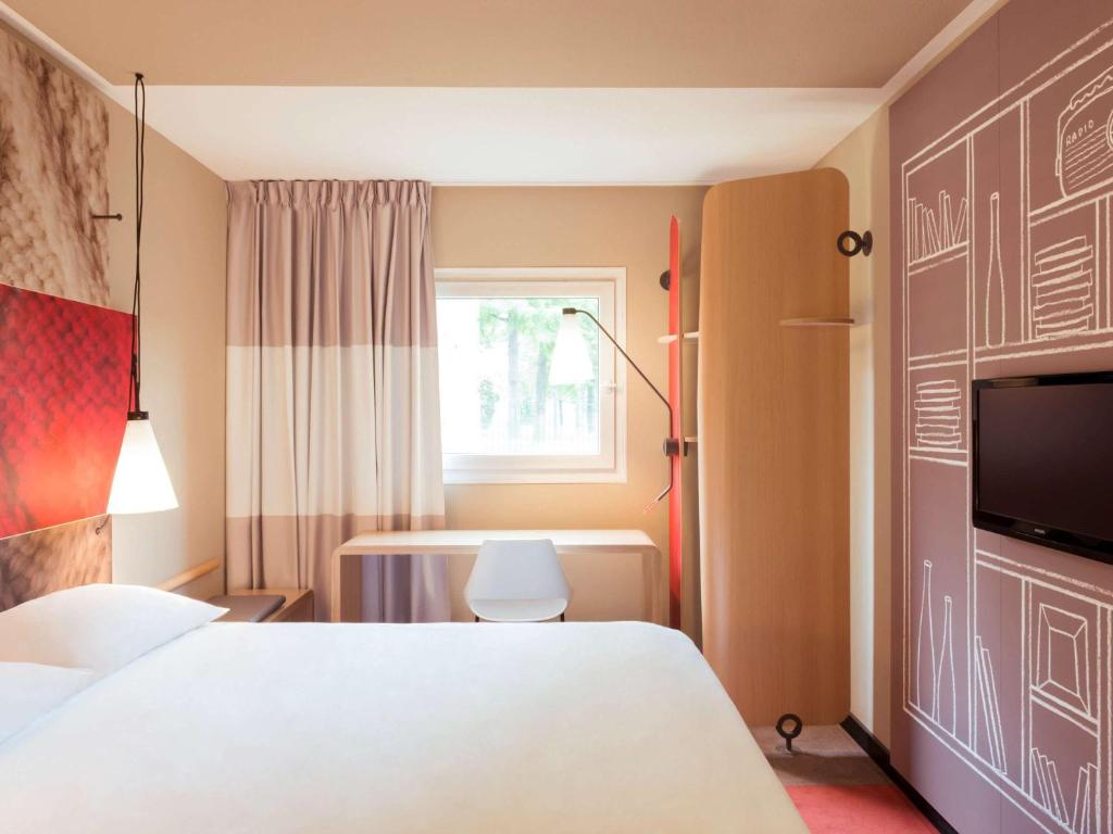 Hotel Ibis Tatui في تاتوي: غرفة نوم بسرير ابيض ونافذة