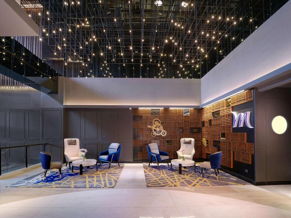 a lobby with chairs and a sign on a wall at Mercure Surabaya Manyar in Surabaya