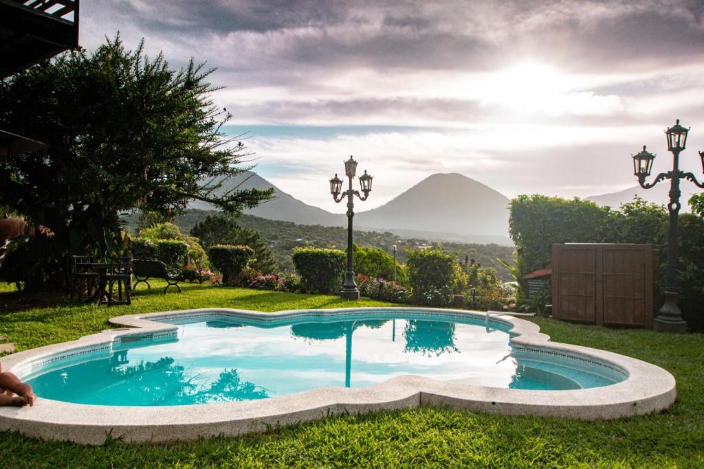 a swimming pool in the grass with a mountain in the background at Hotel Juayua in Juayúa