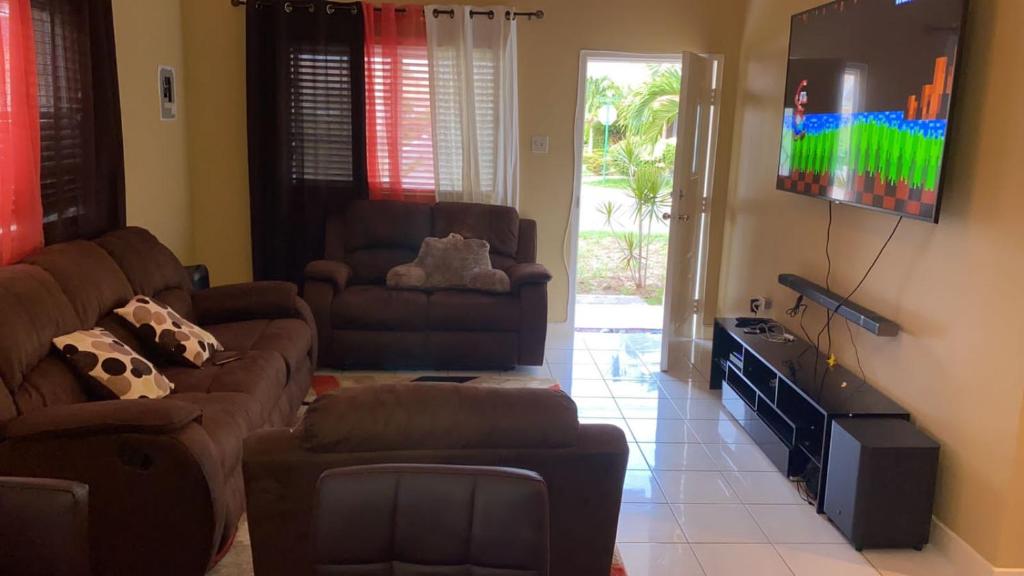 a living room with a couch and a flat screen tv at Luxurious Secret Escape in Portmore