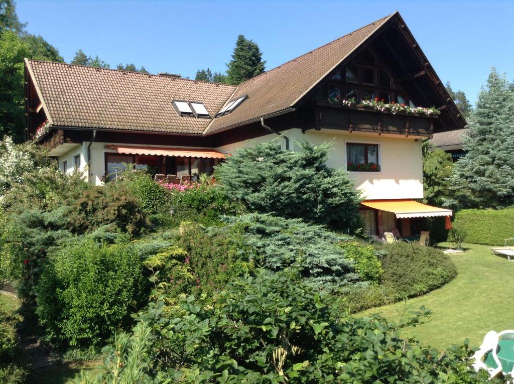 a house with a brown roof and some bushes at Ferienwohnungen Salmen in Pörtschach am Wörthersee