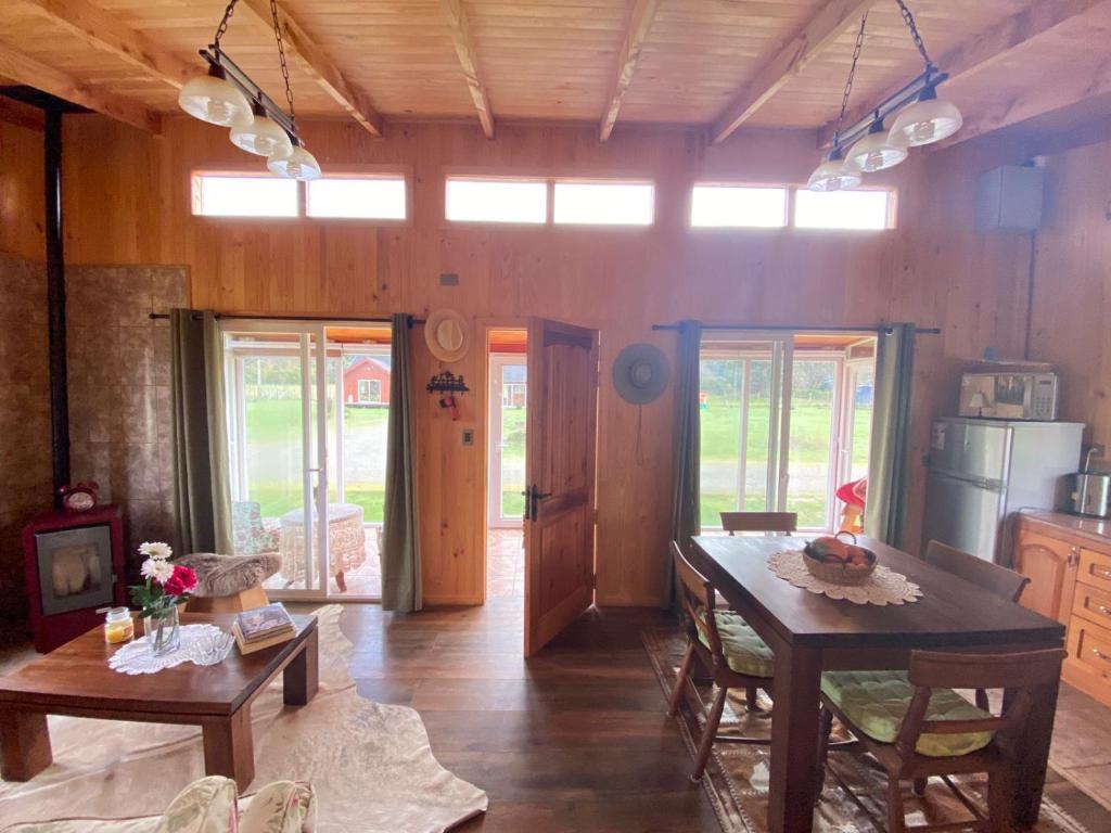 Una cocina con suelos de madera y una mesa y sillas. en Cabañas Teresa Frutillar, en Frutillar