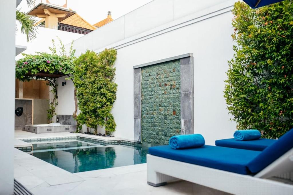 an outdoor patio with a swimming pool and blue furniture at Kamil Villas in Seminyak