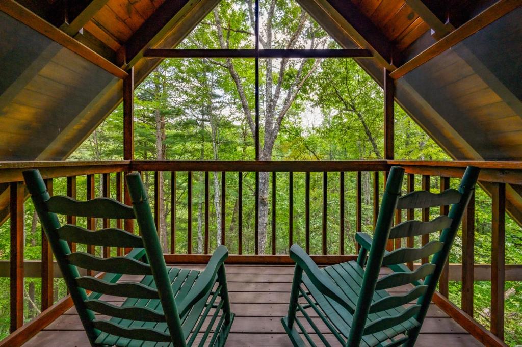 two green rocking chairs sitting on a porch at GYPSY ROAD - Privacy! Log Cabin with Hot Tub, WiFi, DirecTV and Arcade in Sevierville