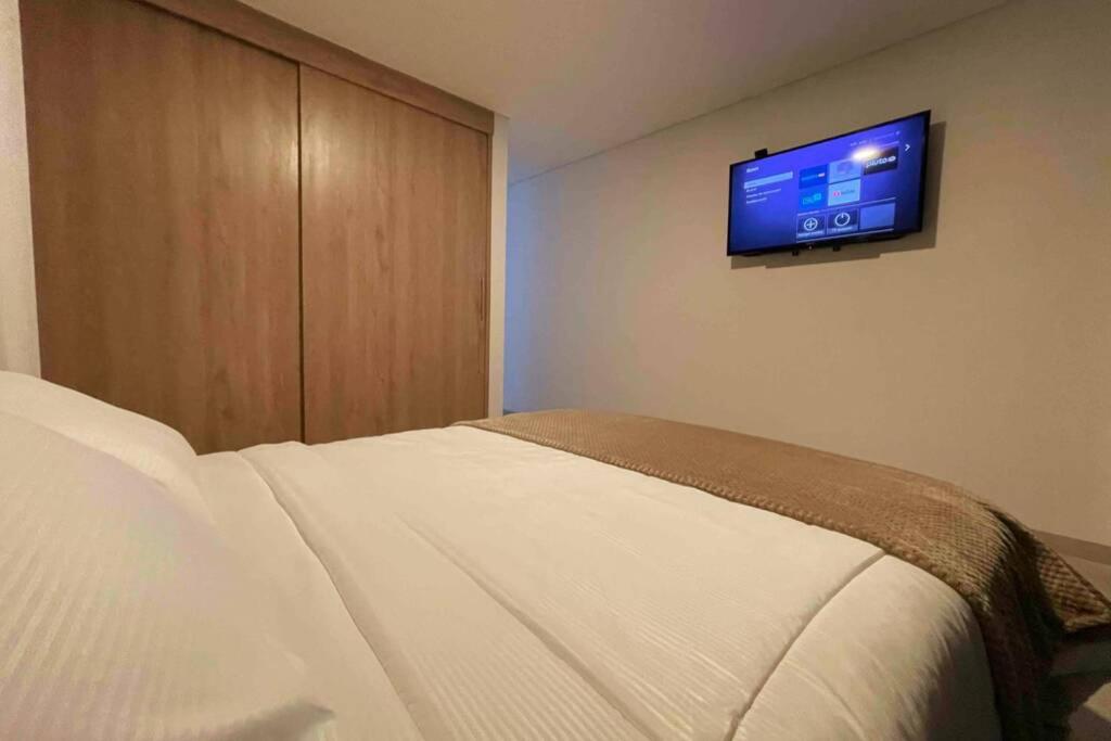 een slaapkamer met een bed en een flatscreen-tv aan de muur bij Cómodo apartamento con excelente ubicación in Armenia