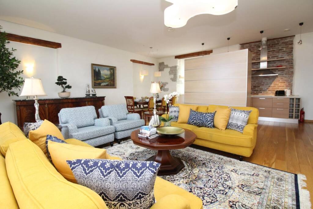 a living room with yellow couches and a table at Tallinn City Apartments - Luxury 3 bedroom, sauna, views in Tallinn