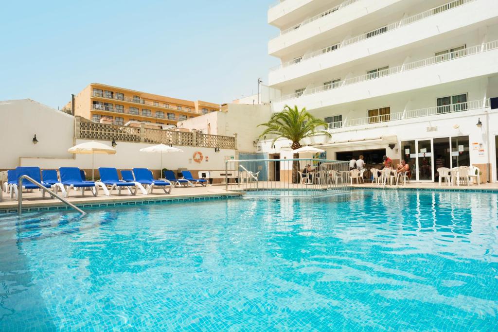 einem großen Pool mit blauen Stühlen und einem Gebäude in der Unterkunft HSM Reina del Mar in El Arenal