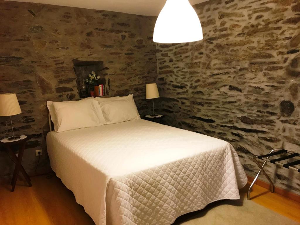 um quarto com uma cama e uma parede de pedra em Casa da Caroline em Freixo de Espada à Cinta