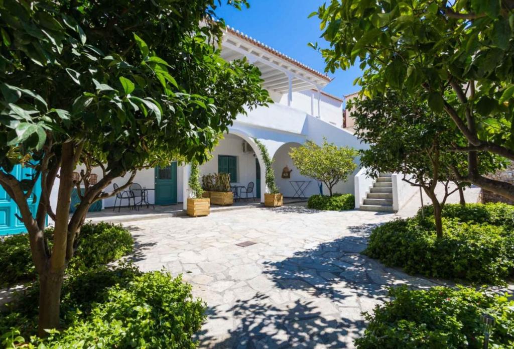 a courtyard with trees in front of a house at Aria Apartments in Spetses