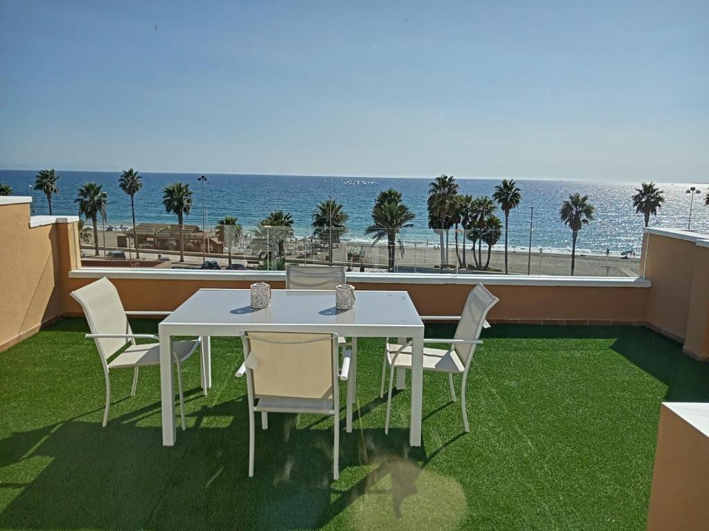 a white table and chairs on a balcony with the ocean at Coqueto estudio-ático EN PRIMERA LÍNEA DE PLAYA CON PRECIOSAS VISTAS AL MAR in Almería