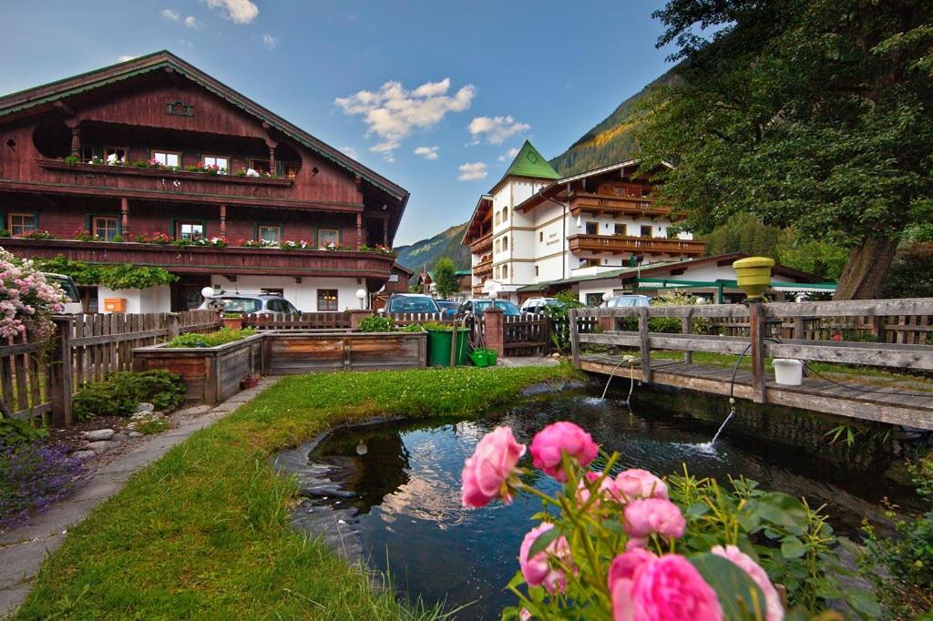 une rivière aux fleurs roses devant les bâtiments dans l'établissement Landhotel Denggerhof, à Mayrhofen