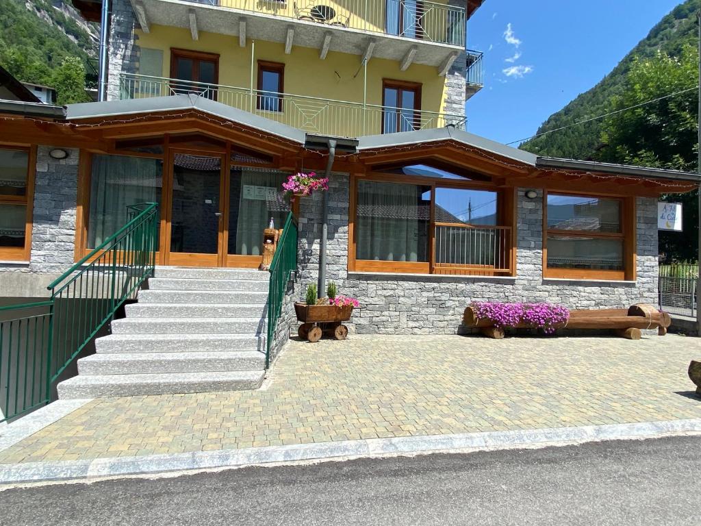 - un bâtiment avec des escaliers et des fleurs devant dans l'établissement B&B A fil di cielo, à Val Masino