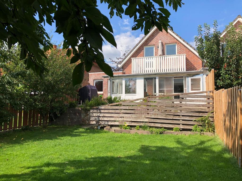 ein Haus mit einem Holzzaun im Hof in der Unterkunft Baumberger Ferienhaus mit Garten & Wintergarten mit 3 Schlafzimmern & 2 Bädern in Nottuln