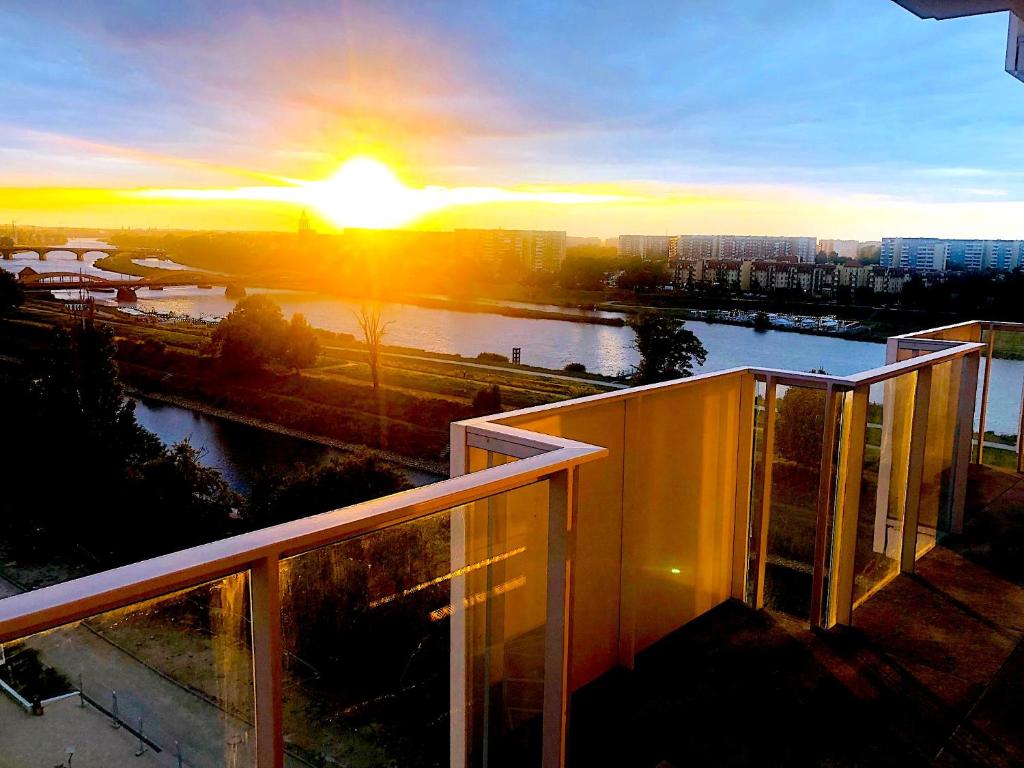 a view of the sunset from the balcony of a building at Apartament z tarasem i widokiem na Odrę in Wrocław