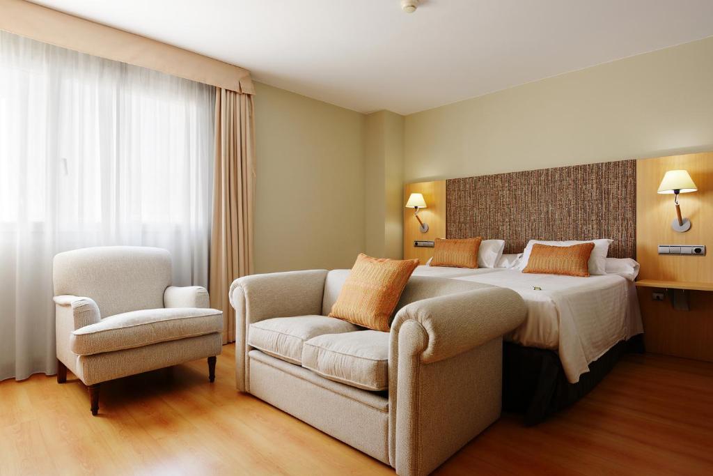 ein Hotelzimmer mit einem Bett und einem Stuhl in der Unterkunft U Hotel Villa-Gomá in Saragossa