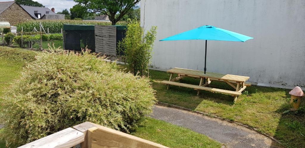 a picnic table with a blue umbrella in a yard at Les 3 mômes in Pontorson