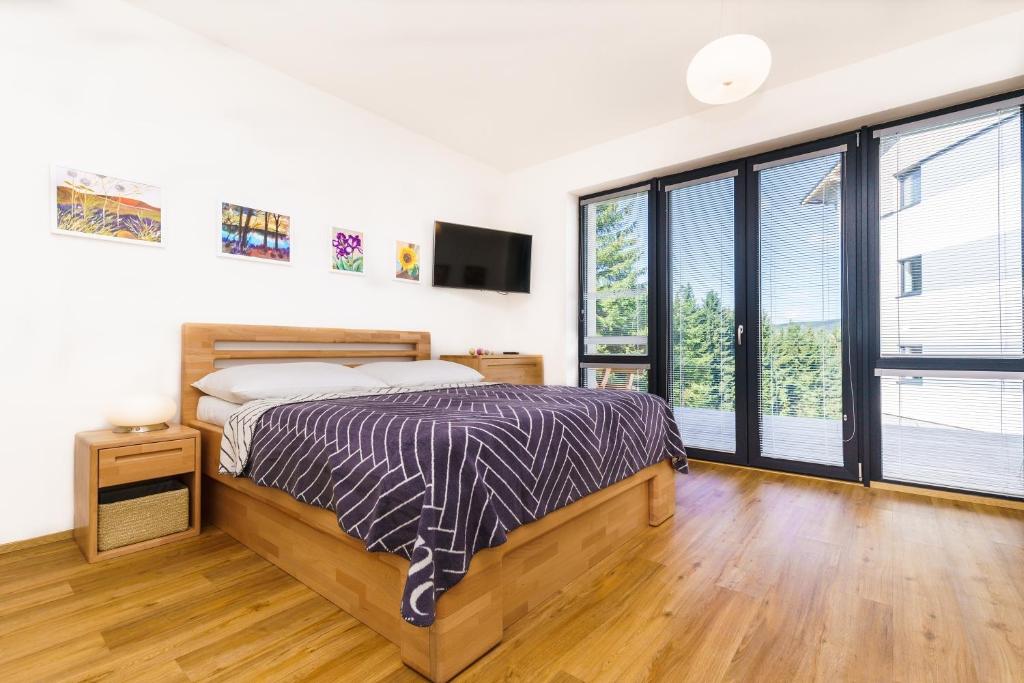 a bedroom with a bed and large windows at Horský apartmán Temari 6 Klínovec in Loučná pod Klínovcem