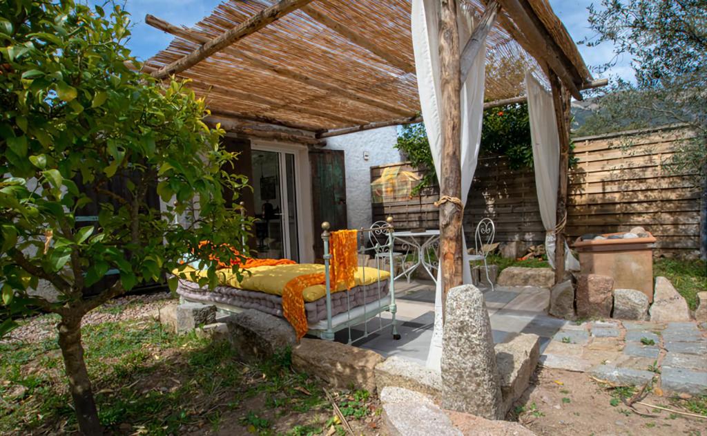d'une terrasse avec un lit sous une pergola. dans l'établissement L'attelu avec piscine au coeur du maquis, à Carbuccia