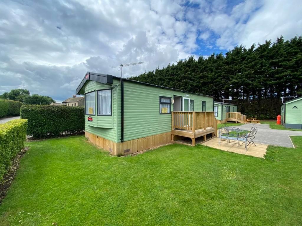 a green tiny house in a yard with a deck at Lido leisure park in Knaresborough