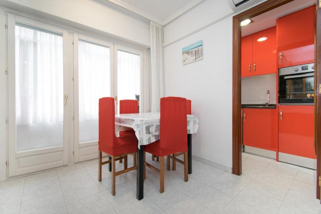 uma cozinha com uma mesa e cadeiras vermelhas em 016 Happiness Apartment - Alicante Holiday em Torrevieja