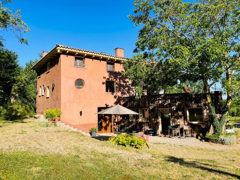 une grande maison en briques avec un parasol devant elle dans l'établissement CASA DEL AGUA - La Rioja, à Santa Coloma