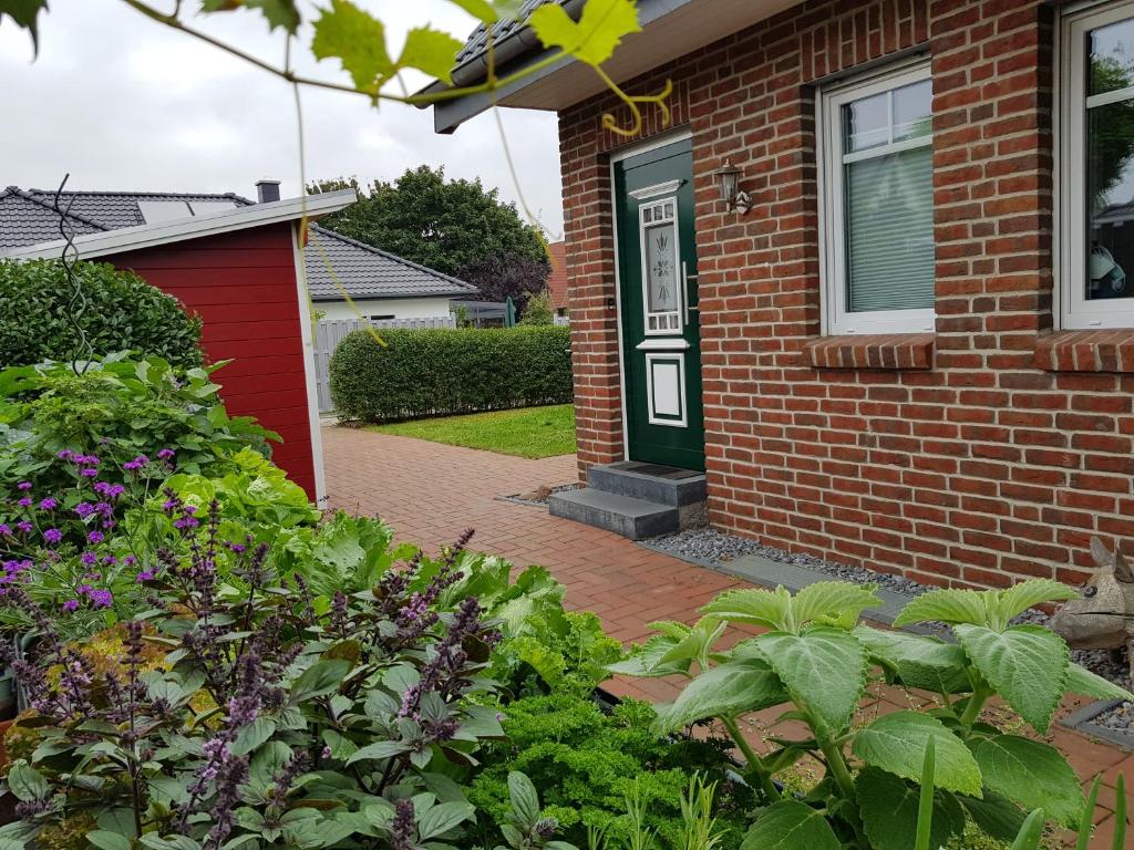 una casa de ladrillo con una puerta verde y algunas plantas en Ferienwohnungen Liliencron - Fewo I, en Enger