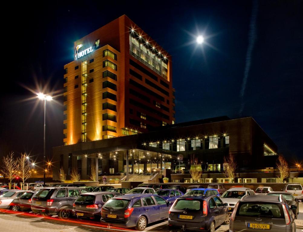 un parking avec des voitures garées devant un bâtiment dans l'établissement Hotel Duiven bij Arnhem A12, à Duiven
