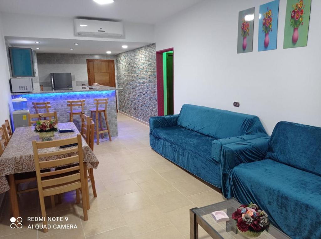 a living room with a blue couch and a kitchen at Palmera Beach Chalet - Families Only in Ain Sokhna