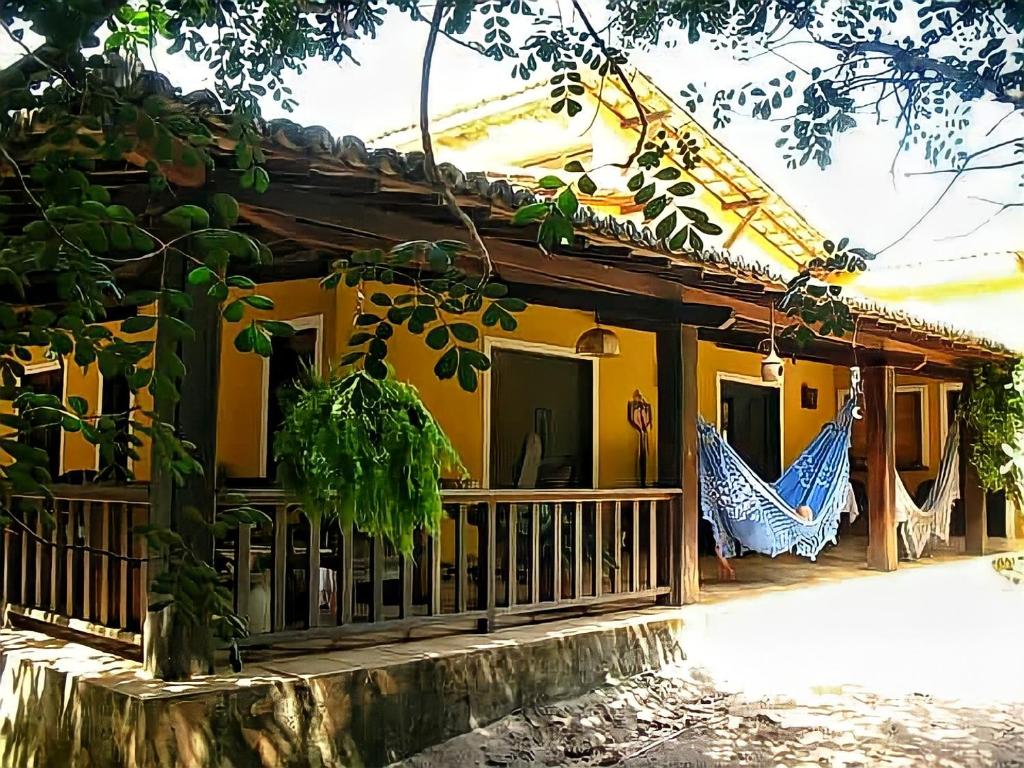 琵琶的住宿－Casa Cajueiro em Pipa，黄色房子,外面设有门廊和吊床