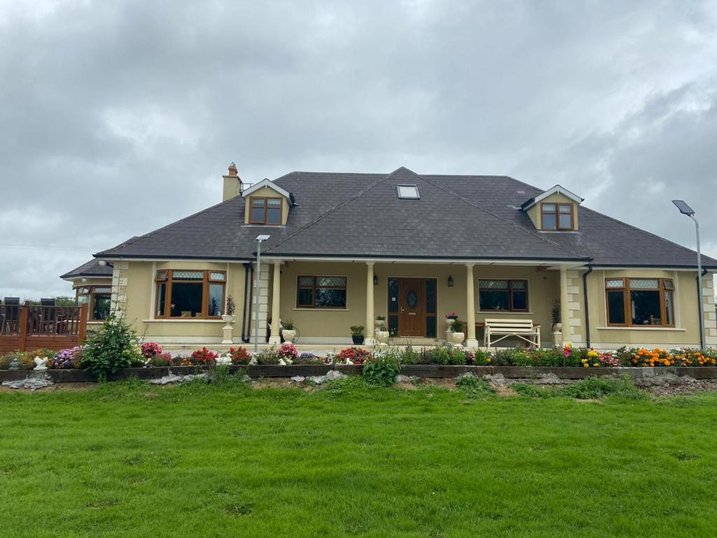 a yellow house with flowers in a yard at Motorwaylodge Kilcoran Cahir E21RK60 in Cahir