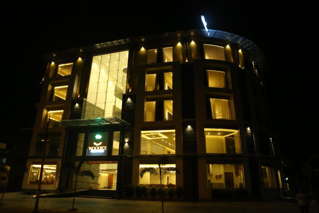 un edificio iluminado con un reloj en él por la noche en Woodies Bleisure Hotel, en Kozhikode
