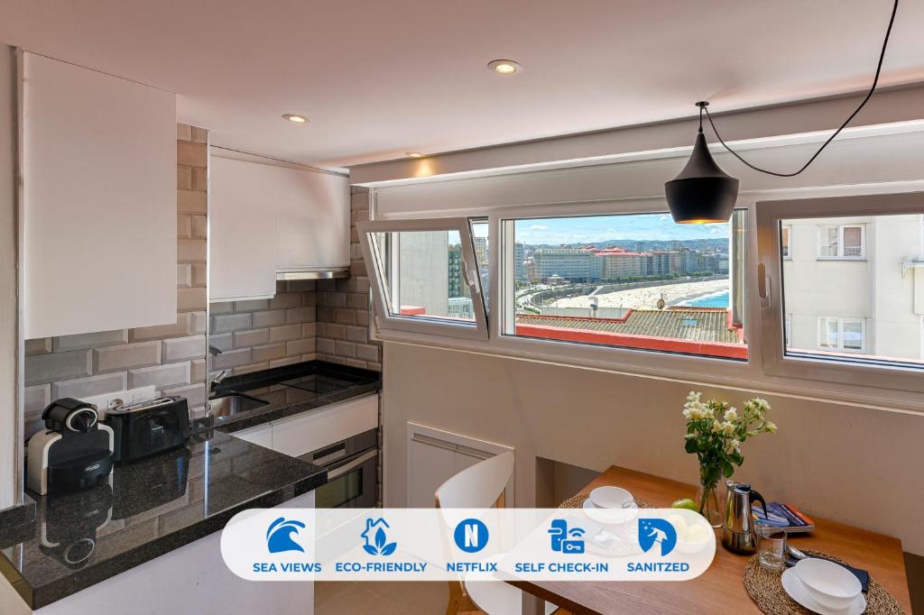 eine kleine Küche mit einem Tisch und einem Fenster in der Unterkunft Orzan Beach 2 by TheBlueWaveApartments com in A Coruña