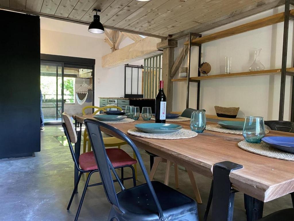 a wooden table with a bottle of wine and chairs at Moulin de Vibrac in Vibrac