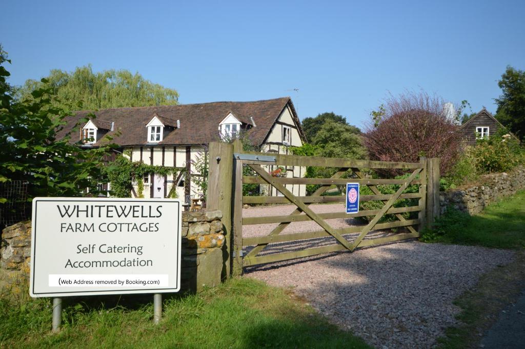 a gate with a sign in front of a house at Whitewells Farm Cottages in Great Malvern