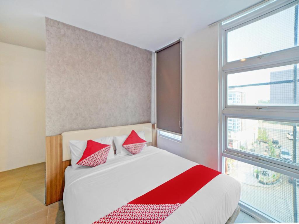 een slaapkamer met een bed met rode kussens en een raam bij Super OYO 90559 Gamacity Residence in Pulauberayan Dadap