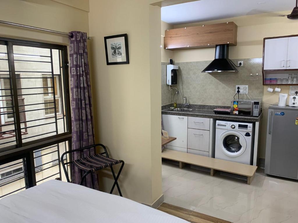 a kitchen with a washing machine and a washer and dryer at Pearl by Olys Apartment in Kolkata