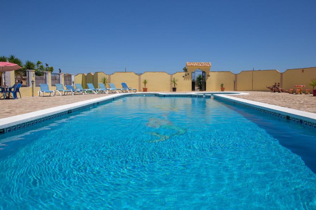 una gran piscina con sillas azules en un complejo en Casa Ana - delightful semi-detached villa with large swimming pool, tennis court and huge gardens plus Free wifi, en Turre
