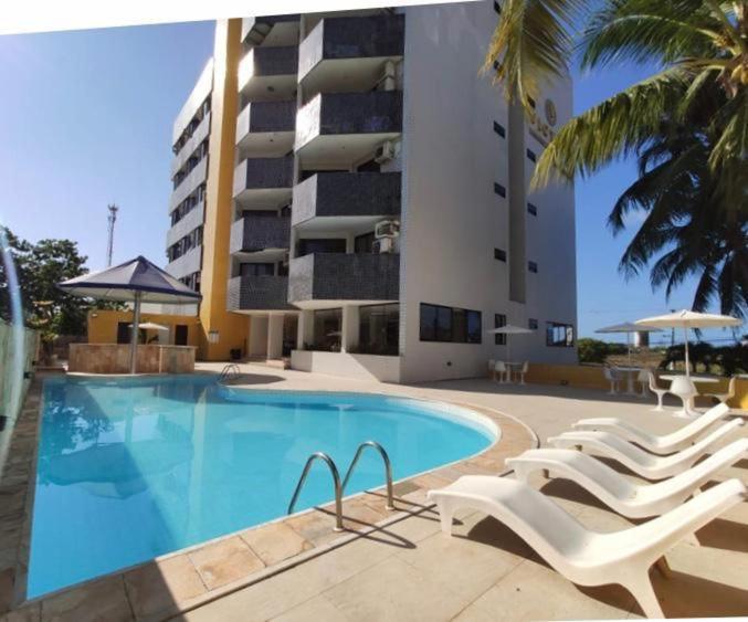 Una piscina con tumbonas y un edificio. en victory flat em Intermares, en Cabedelo