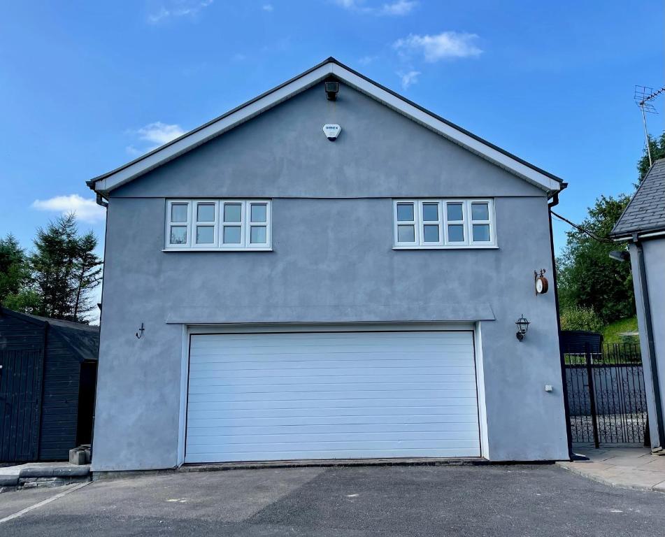 a grey garage with two windows on top of it at The Annex at Pantglas Farm in Pontyclun