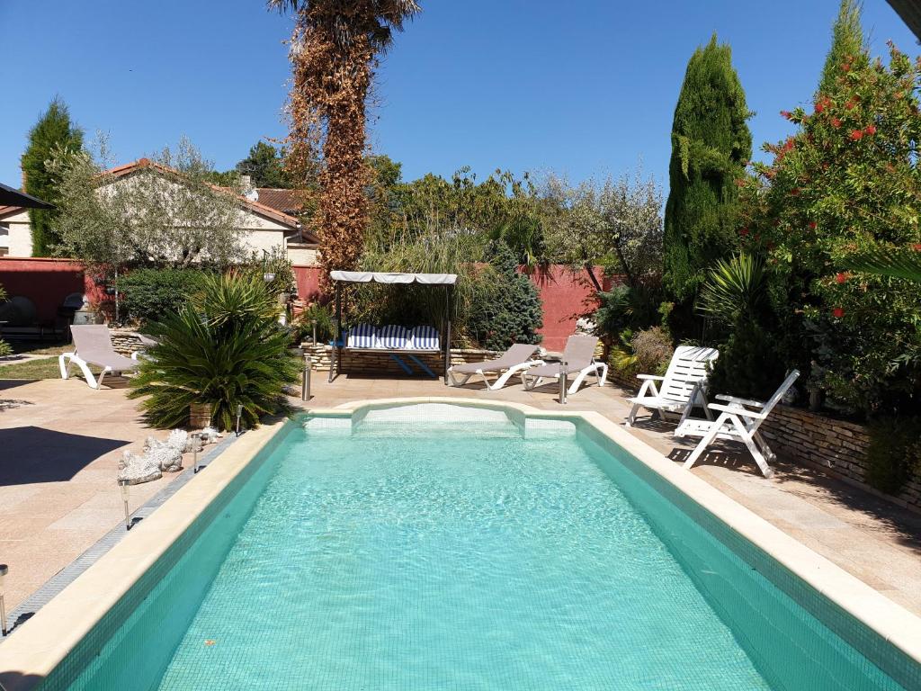 a swimming pool in a yard with chairs and trees at REDHOUSE Studios Roques - Solarium in Roques Sur Garonne