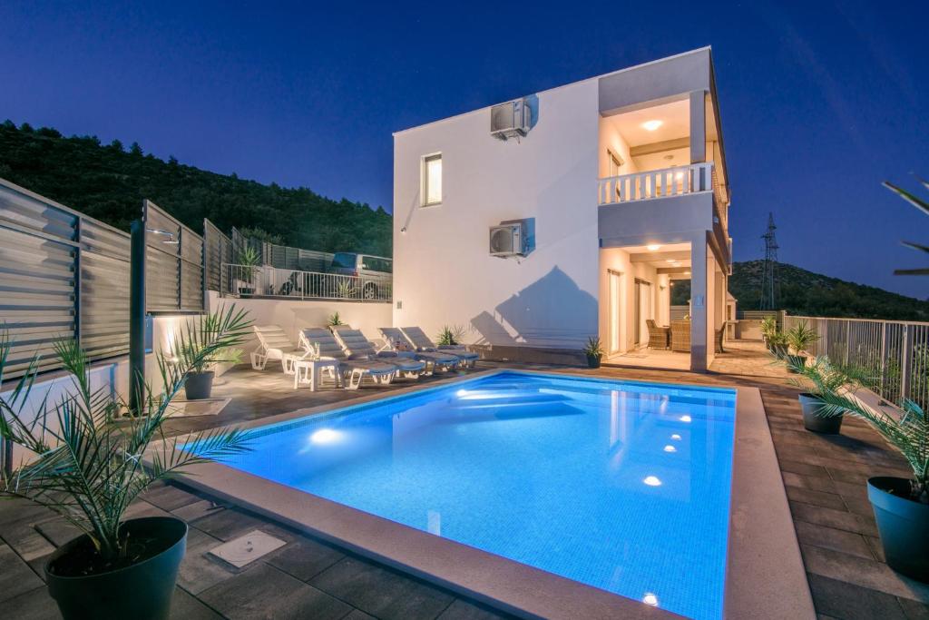 a villa with a swimming pool in front of a house at VILLA Mari with private pool in Marina