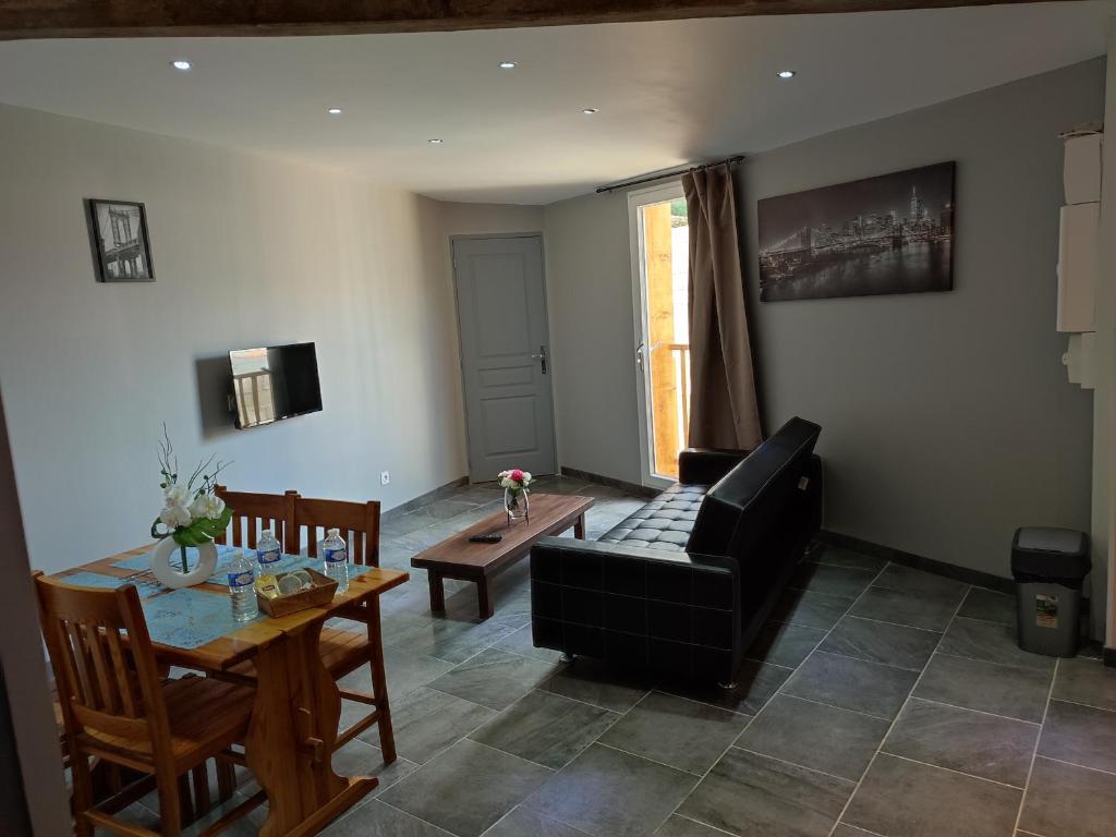 a living room with a black couch and a table at appartement Violette in La Guerche-sur-lʼAubois