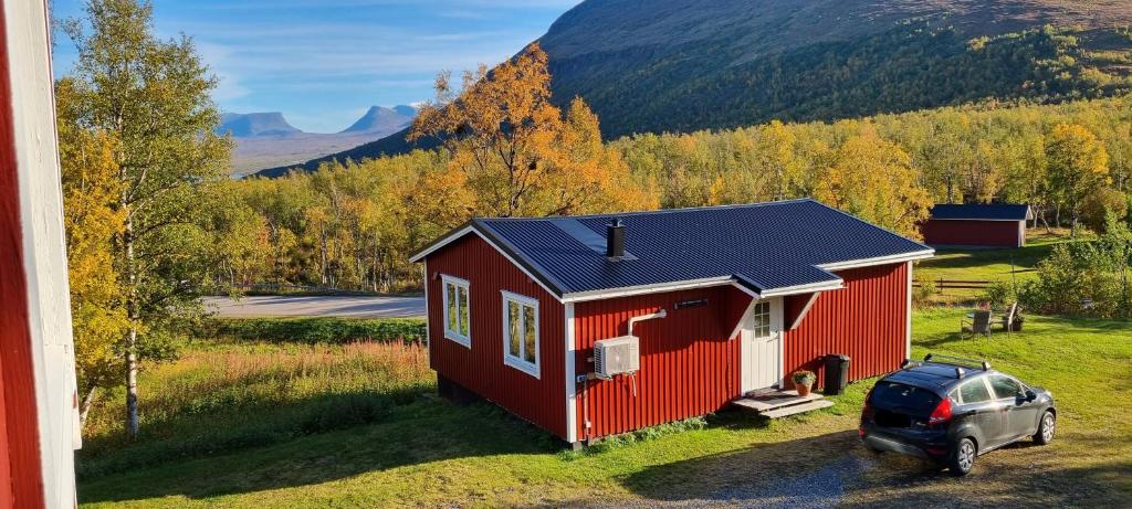 een rood huis met een auto ervoor geparkeerd bij Micke o Ritas stuga in Björkliden