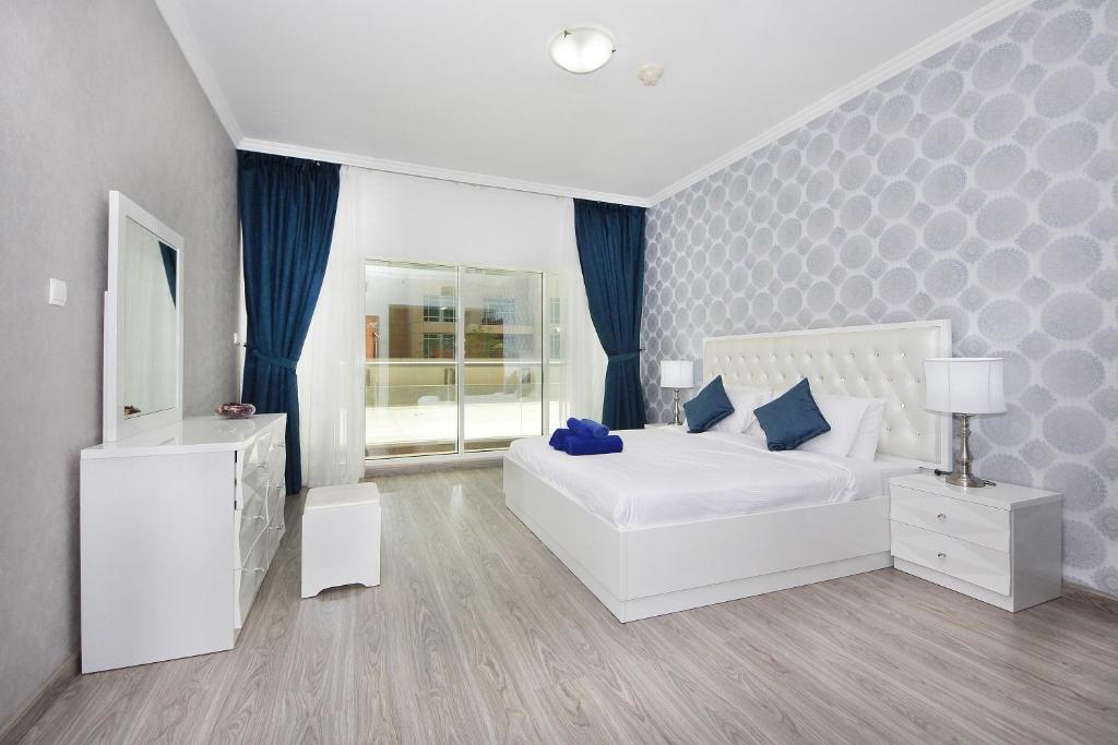 a white bedroom with a white bed and blue pillows at New Arabian Burj Al Nujoom Downtown Dubai in Dubai