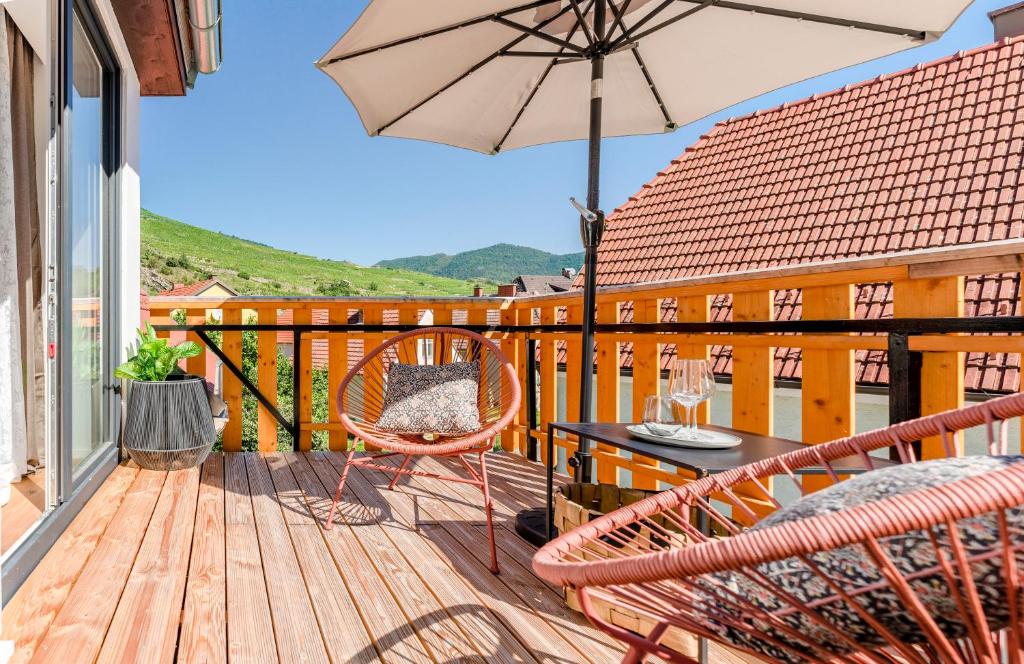 a balcony with a table and chairs and an umbrella at Vinum.Lodge Spitz in der Wachau in Spitz