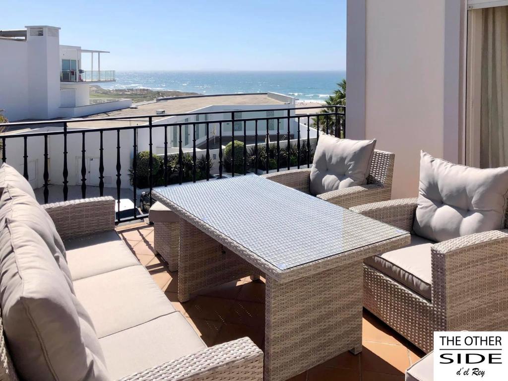 einen Balkon mit einem Tisch, Stühlen und Meerblick in der Unterkunft The other Side D'el Rey Apartment in Amoreira