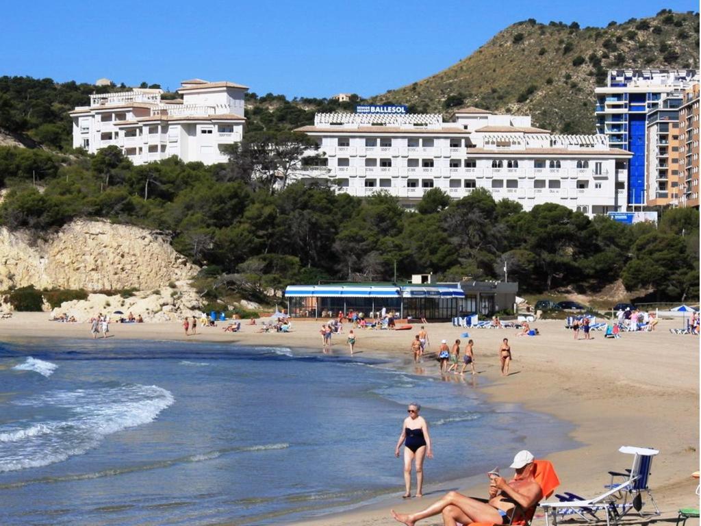 un groupe de personnes sur une plage avec des bâtiments dans l'établissement Ballesol Costablanca Senior Resort mayores de 55 años, à La Cala de Finestra